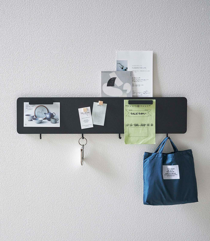 View 12 - Yamazaki black Magnetic Wall Panel with things pinned to it with keys and a bag hanging from hooks