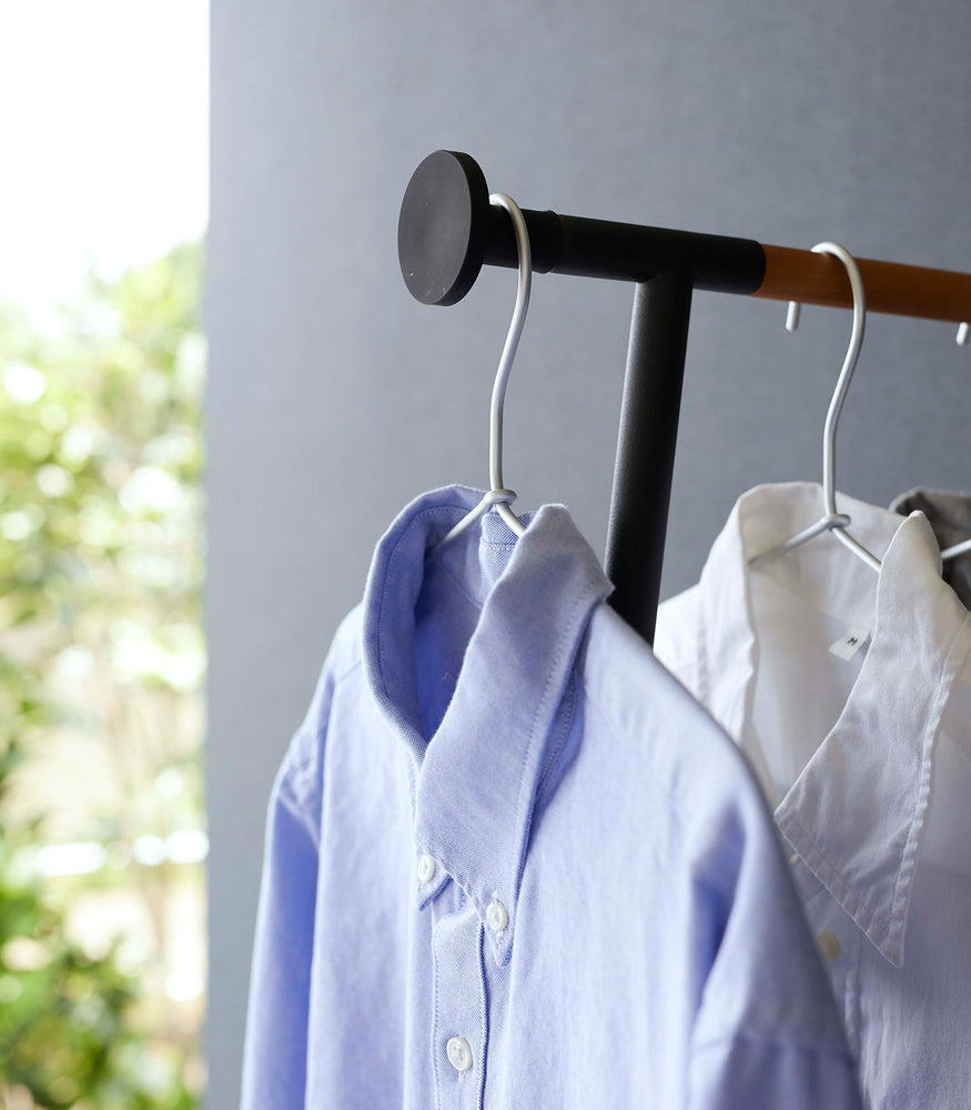View 12 - Close up of collared shirts hung on black Yamazaki Home Clothes Steaming Leaning Pole Hanger