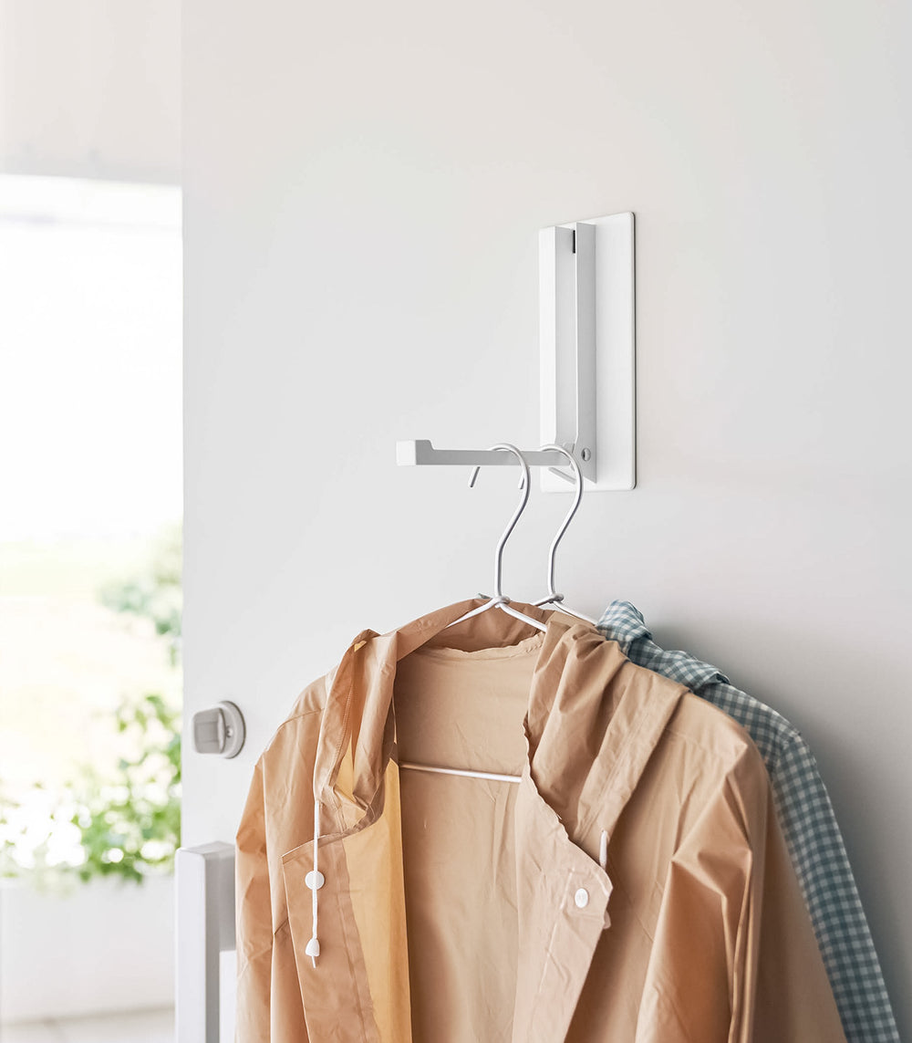 White Yamazaki Home Magnet Folding Hanger with two pieces of clothing hung