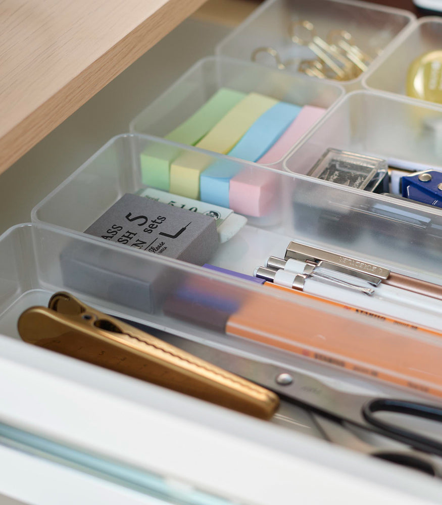 View 38 - Close-up image of three different sizes of stackable clear organizers—small, medium, and large—neatly placed in a desk drawer. Made from transparent material, they accommodate stationery items like pens, paper clips, and sticky notes, showcasing their clarity and stackability