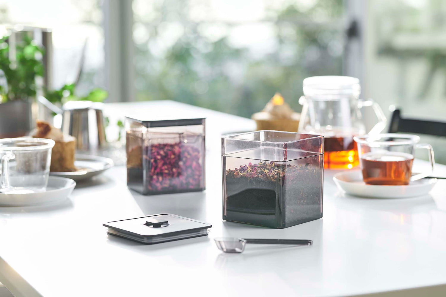 View 11 - Front view of black Vacuum-Sealing Food Container w. Spoon holding tea leaves on tabletop by Yamazaki Home.