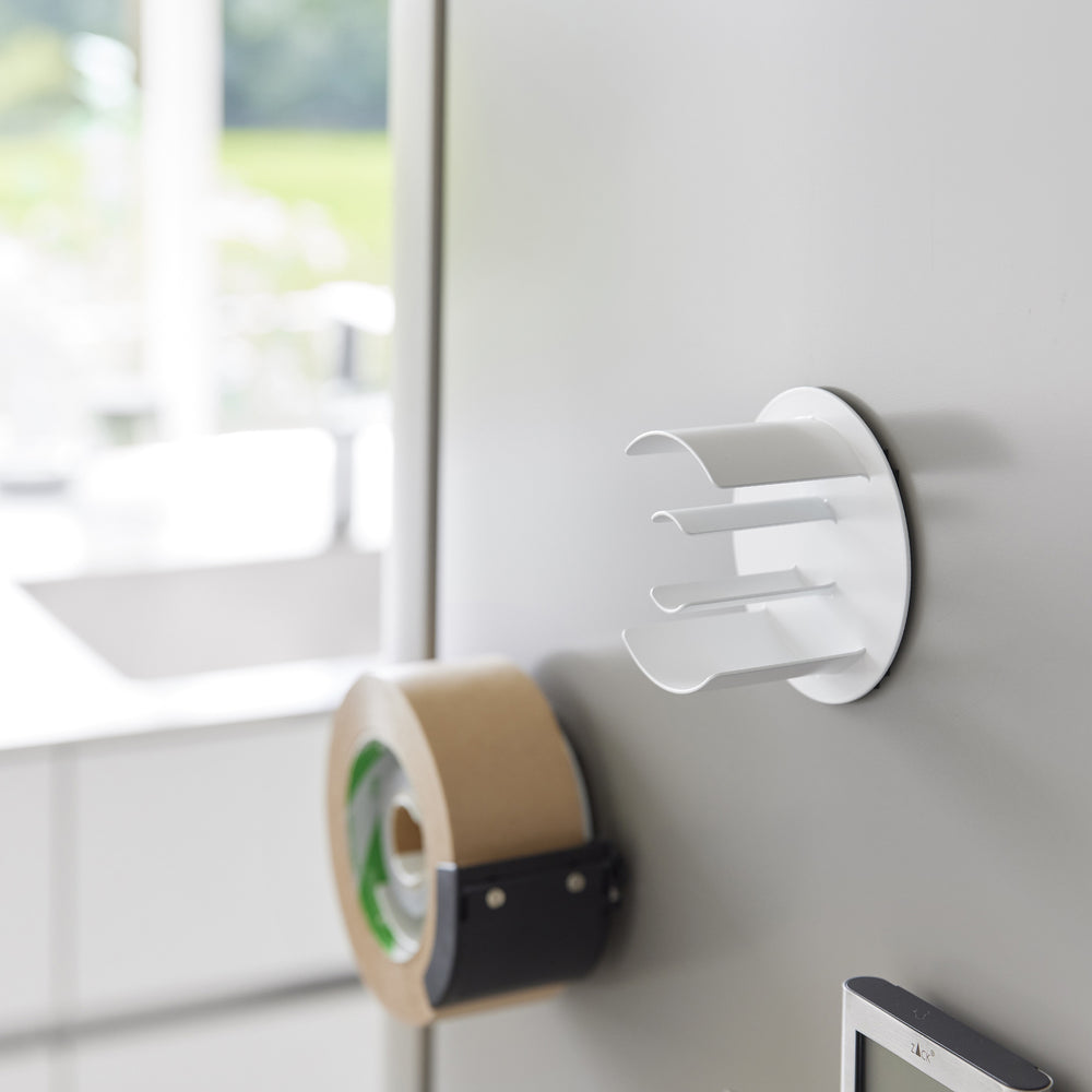 White Yamazaki Home Magnetic Tape Holder attached to a refridgerator