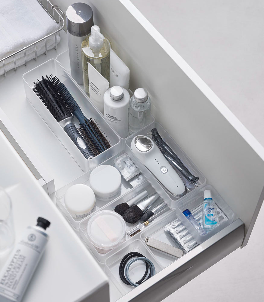 View 21 - Four different sizes of stackable clear organizers—small, medium, large, and deep—are neatly placed in a bathroom drawer. Made from transparent material, they accommodate items like brushes and sanitary products, showcasing their clarity and stackability.