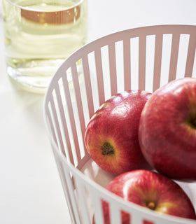 Close up view of white Fruit Basket holding apples on white background by Yamazaki Home. view 3