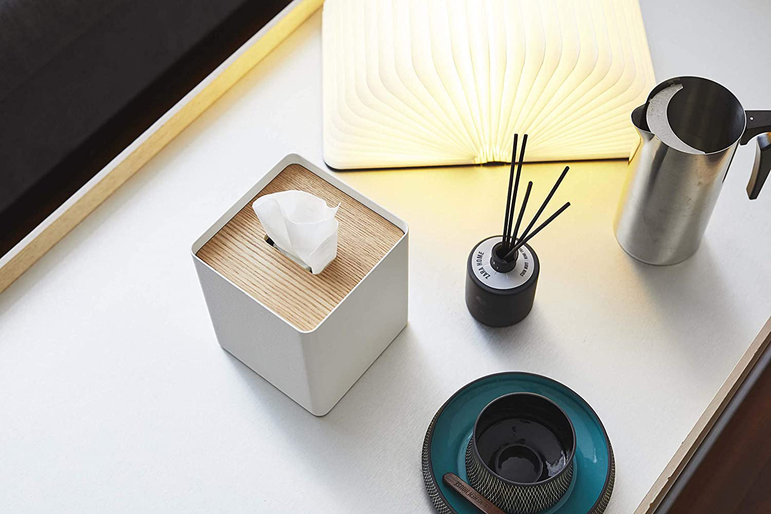 View 6 - Aerial view of white Tissue Case on table next to book light, cup, and décor pieces by Yamazaki Home.