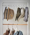 Frontal close up of hats hung on hooks included with white Yamazaki Home Coat Rack with Hat Storage