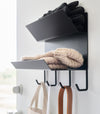 Close-up of the shelves on the Magnetic Entryway Rack by Yamazaki Home in black. Various entryway items are stored on the rack including gloves and a dog leash.