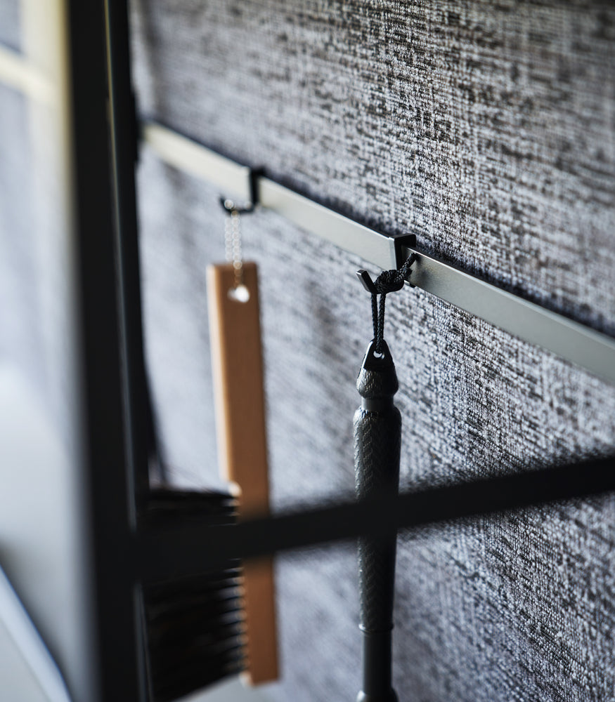View 14 - Image showing items hanging form hooks on the back bar of the Long Console Table by Yamazaki Home in black.