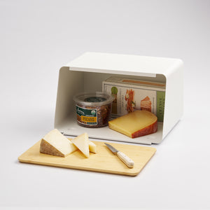 White Tower Bread Box with Cutting Board Lid by Yamazaki Home with snacks and cheese inside, with sliced cheese on the lid.