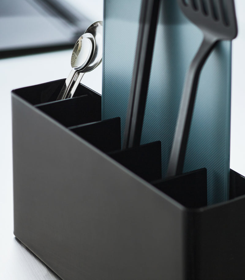 Close-up of a Black Utensil & Thin Cutting Board Holder by Yamazaki Home containing a blue cutting board and black utensils.