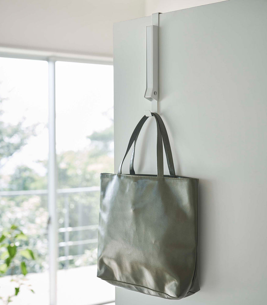 View 4 - White Yamazaki Home Folding Over-The-Door Hanger closed with a purse hung