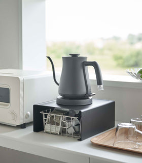 Black Yamazaki Home Stackable Countertop Shelf with a kettle above and a basket of tea underneath view 10