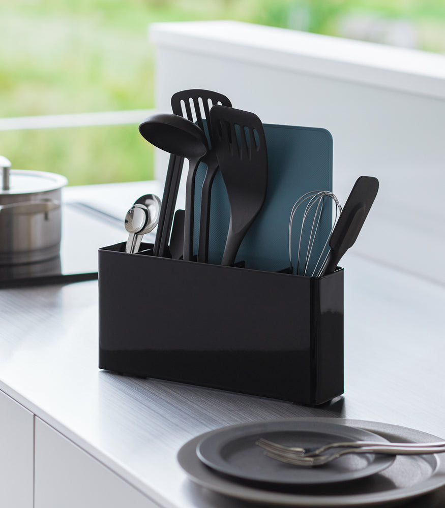 View 9 - Black Utensil & Thin Cutting Board Holder by Yamazaki Home on a kitchen counter, holding various utensils.