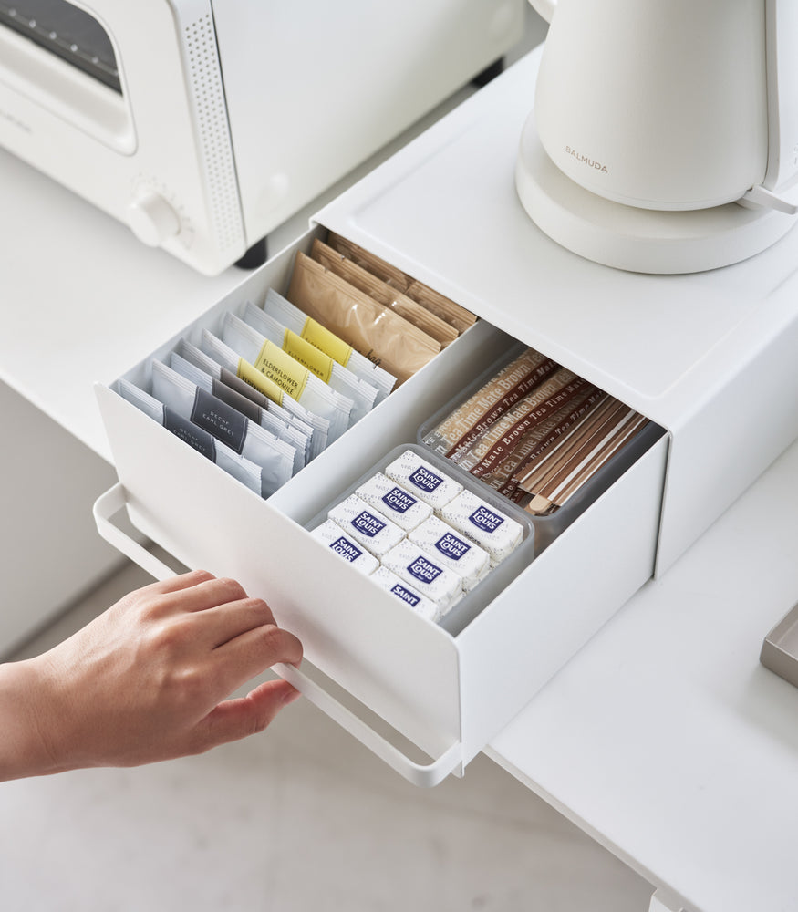 View 4 - Someone is holding a handle of Yamazaki Home White Countertop Rack with Drawer holding tea bags.