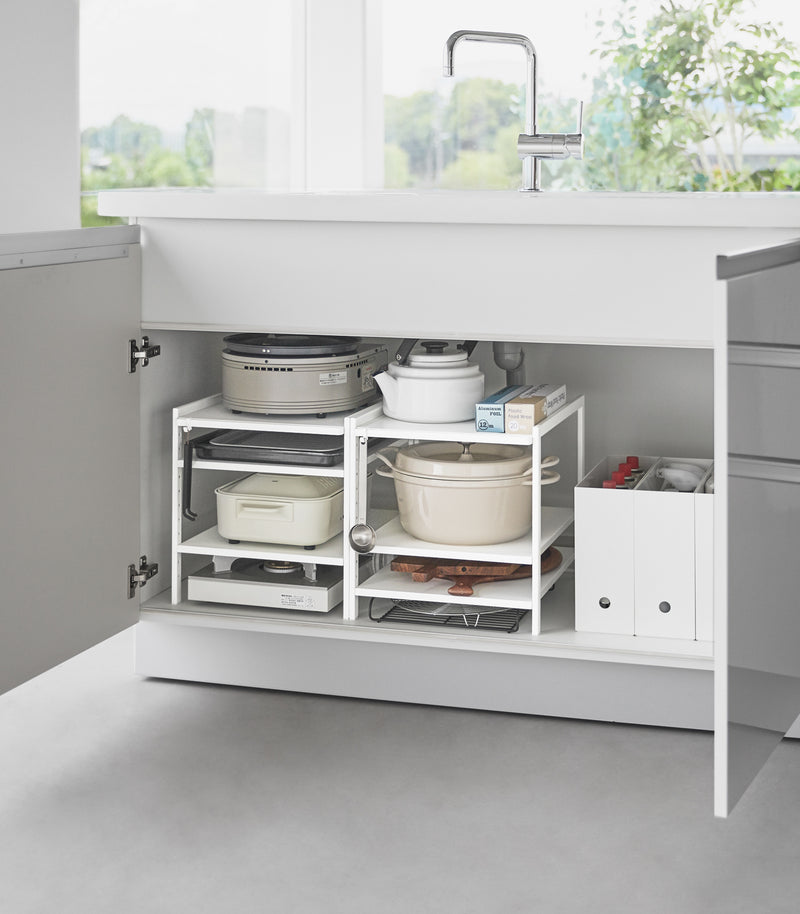 Two of Yamazaki Home Three-Tier Cabinet Storage Rack holding pot and pans and kitchen essentials.