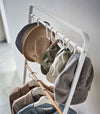 Top-down view of hats hung on hooks included with white Yamazaki Home Coat Rack with Hat Storage