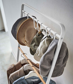 Top-down view of hats hung on hooks included with white Yamazaki Home Coat Rack with Hat Storage view 5