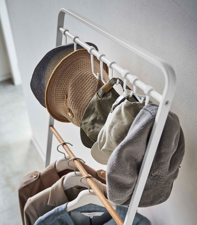 Top-down view of hats hung on hooks included with white Yamazaki Home Coat Rack with Hat Storage