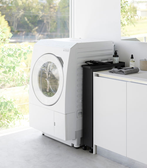 Black Yamazaki Home Slim Rolling Cart stored in a tight corner of a laundry room