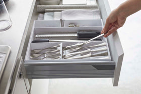 Side view of person placing fork in white Expandable Cutlery Storage Organizer by Yamazaki Home. view 17