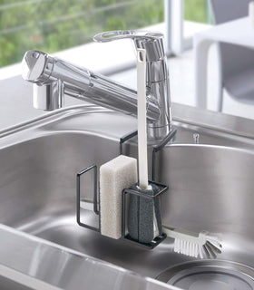 Black Steel Yamazaki Home Faucet-Hanging Sponge & Brush Holder storing a sponge and two brushes view 10