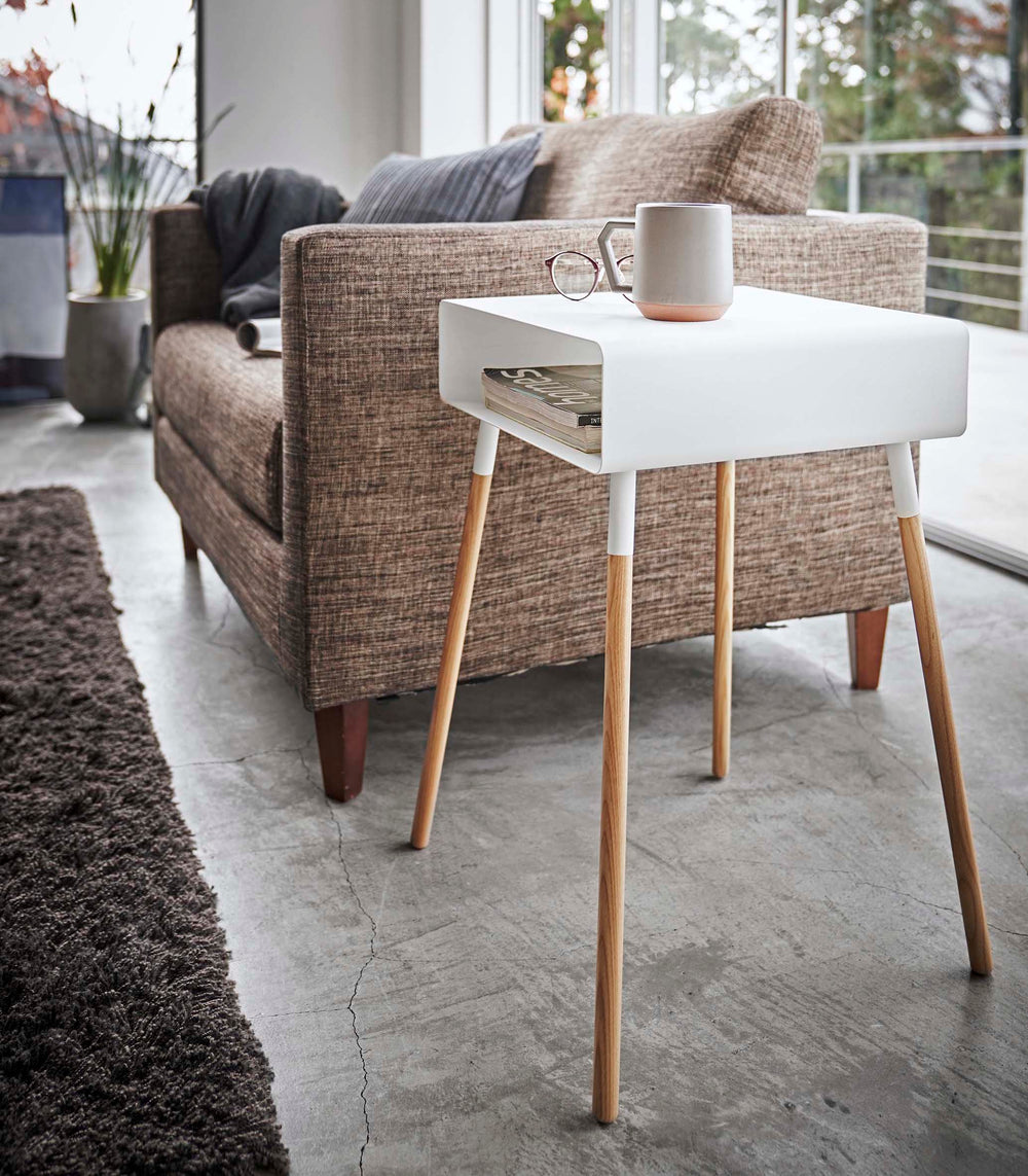 White Storage Table holding books and coffee in living room by Yamazaki Home.