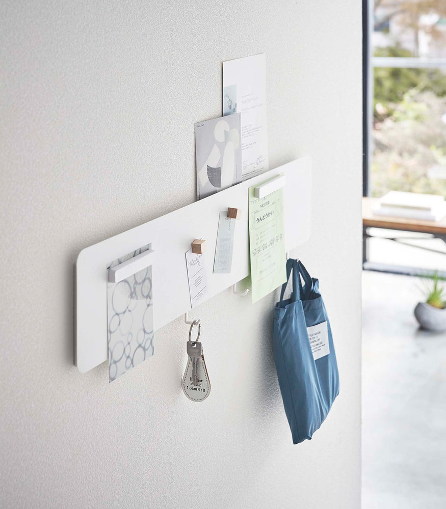 View 3 - Side view of a Yamazaki white Magnetic Wall Panel with keys and a bag hanging from hooks