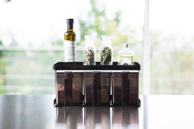 Front view of black Pantry Organizer holding baking ingredients and upper shelf holding spices and oil by Yamazaki Home. view 10