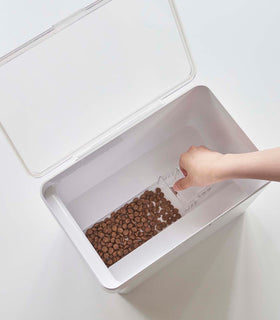 Aerial view of person scooping pet food out of white Airtight Food Storage Container on white background by Yamazaki Home. view 21