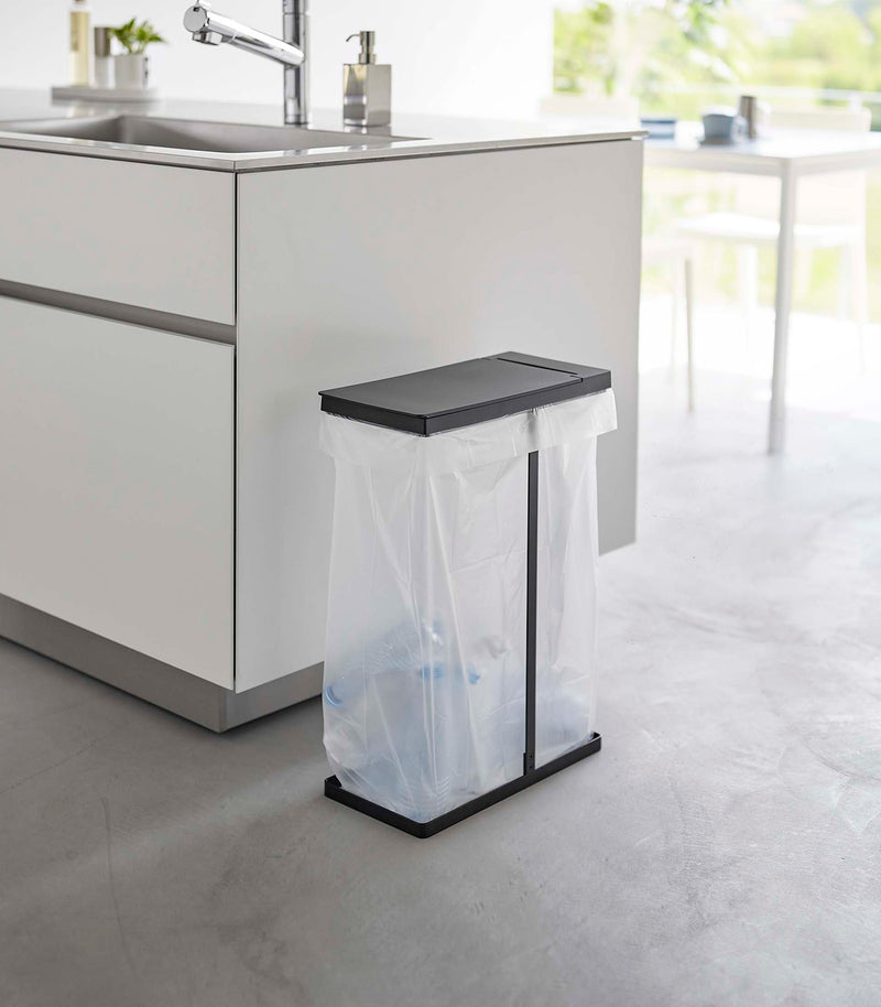 Black Yamazaki Home Lidded Garbage Bag Holder next to a kitchen sink
