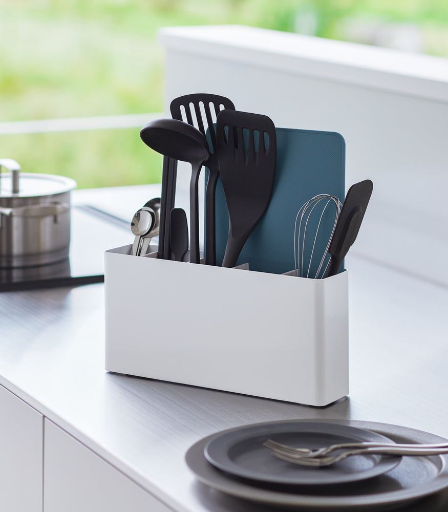 View 2 - White Utensil & Thin Cutting Board Holder by Yamazaki Home on a kitchen counter, holding various utensils.