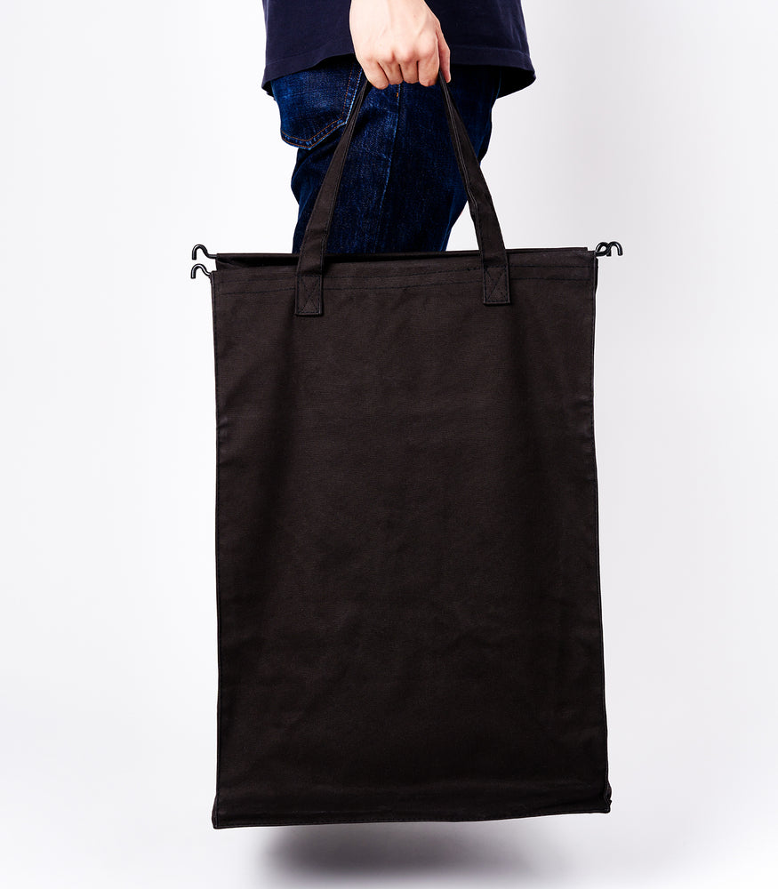 View 12 - Side view of a person holding the liner of the large Laundry Hamper with Cotton Liner in black by Yamazaki Home by the handles.
