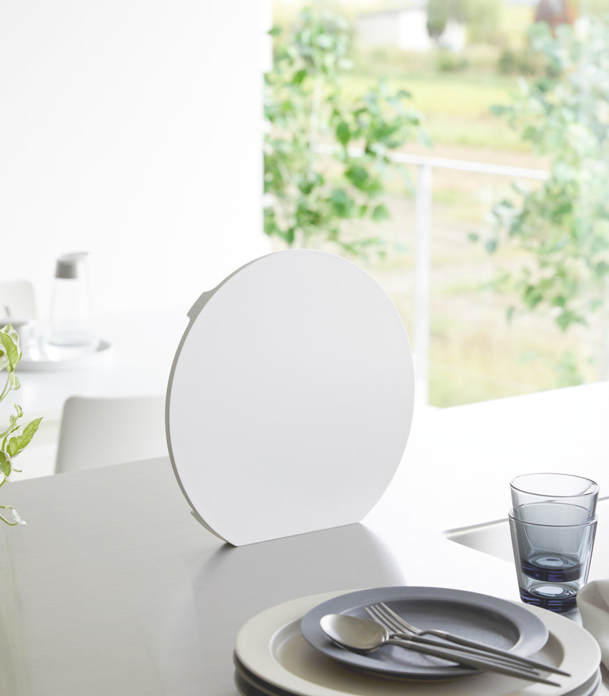 View 2 - A white Yamazaki Round Magnetic Cutting Board standing on a counter.