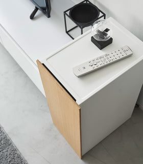 A remote controller and a small object are placed on the white cabinet, showcasing how the cabinet blends beautifully into the room as a piece of furniture. view 6