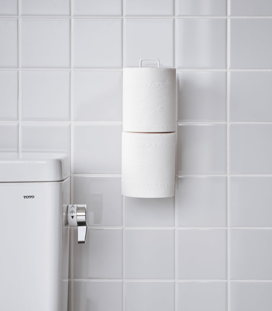 View 7 - Frontal view of white Yamazaki Home Traceless Adhesive Toilet Paper Holder attached to a bathroom wall