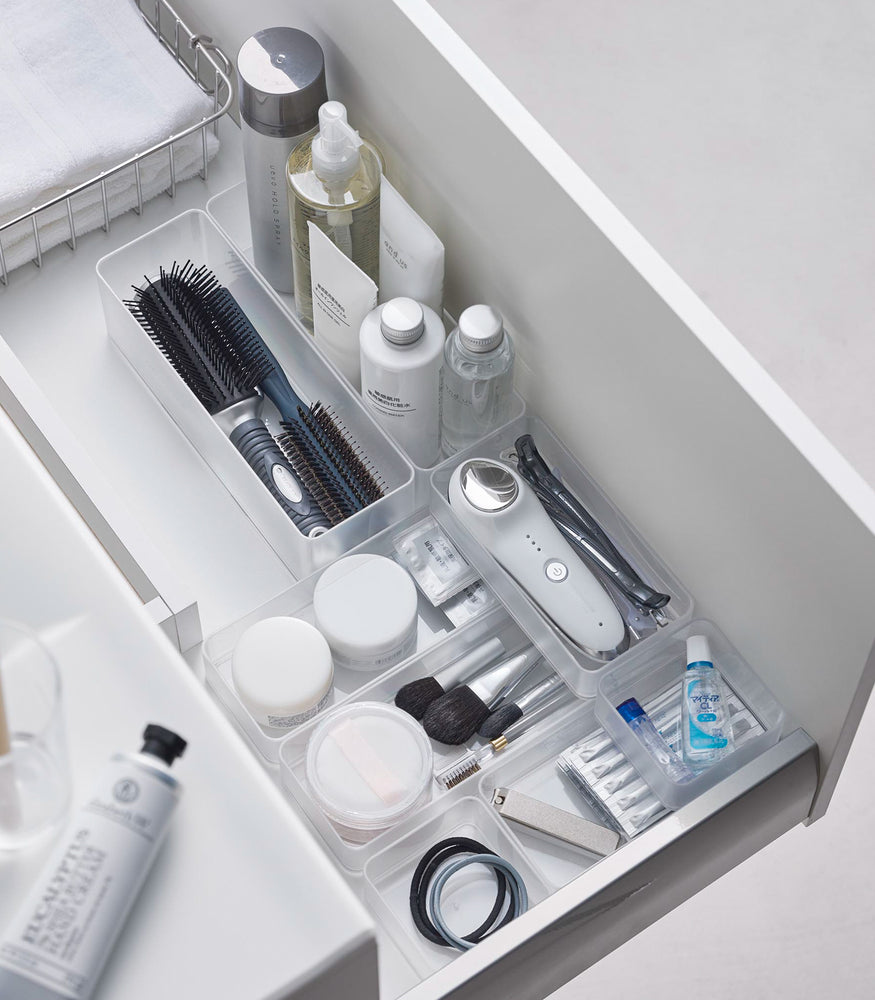 View 37 - Four different sizes of stackable clear organizers—small, medium, large, and deep—are neatly placed in a bathroom drawer. Made from transparent material, they accommodate items like brushes and sanitary products, showcasing their clarity and stackability.