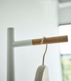 Close up of the top of a white Yamazaki Coat Rack with a coat hanger on it