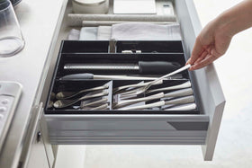 Side view of person grabbing fork out of black Expandable Cutlery Storage Organizer by Yamazaki Home. view 26