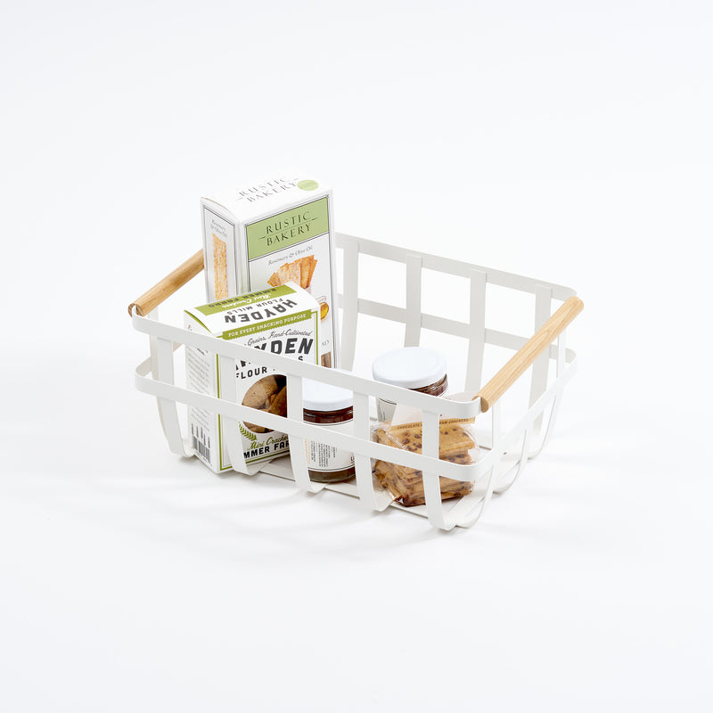 A white Yamazaki Home Tosca storage basket with a light wood handle, containing cleaning sprays.