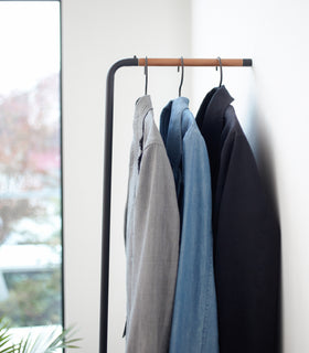 Close up side view of black Slim Leaning Coat Rack displaying jackets by Yamazaki Home. view 5