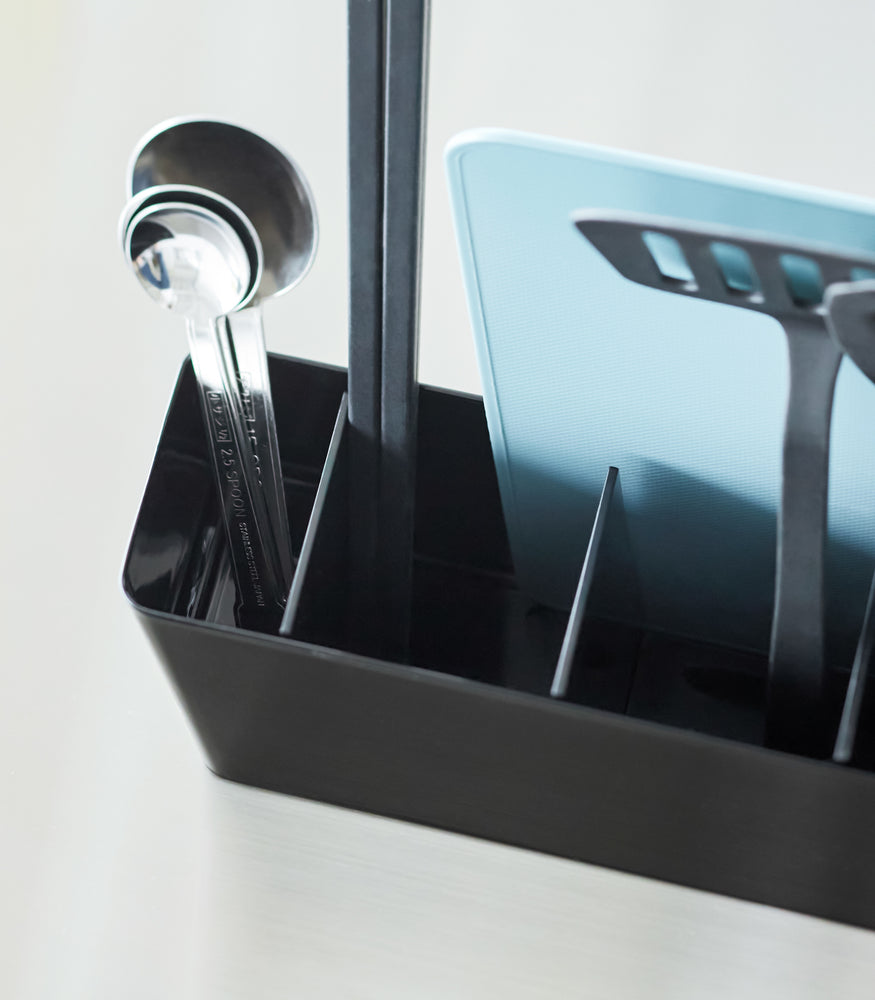 View 13 - Close-up of a Black Utensil & Thin Cutting Board Holder by Yamazaki Home containing a blue cutting board and black utensils.
