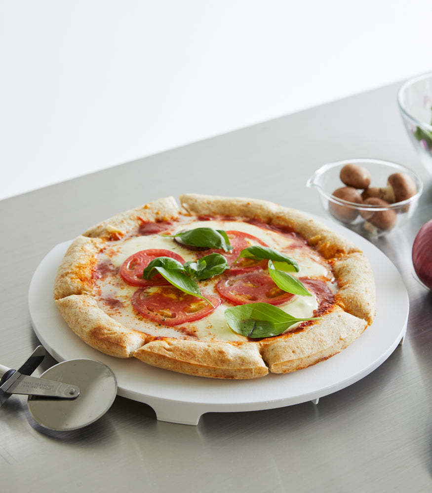 View 5 - A white Yamazaki Round Magnetic Cutting Board holding a pizza.