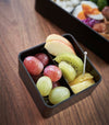 Close up aerial view of black Vacuum-Sealing Bento Box holding fruit by Yamazaki Home.