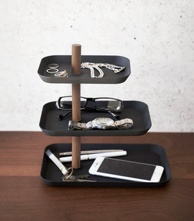 Side view of Yamazaki Home Black Rin Series 3-Tiered Accessory Tray with accessories displayed such as a phone or glasses view 12