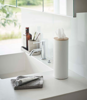 Large White Yamazaki Home Round Tissue Case on a bathroom sink counter view 19