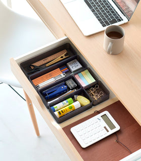 Three different sizes of stackable clear organizers in black —small, medium, and large—are neatly placed in a desk drawer. Made from transparent material, they accommodate stationery items like pens, paper clips, and sticky notes, showcasing their clarity and stackability. view 63