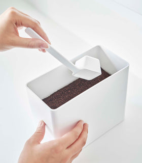 Scooping out coffee from white Yamazaki Home coffee storage container with measuring spoon view 5