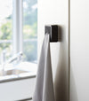 Close up of black Yamazaki Home Traceless Adhesive Towel Holder with a towel inserted