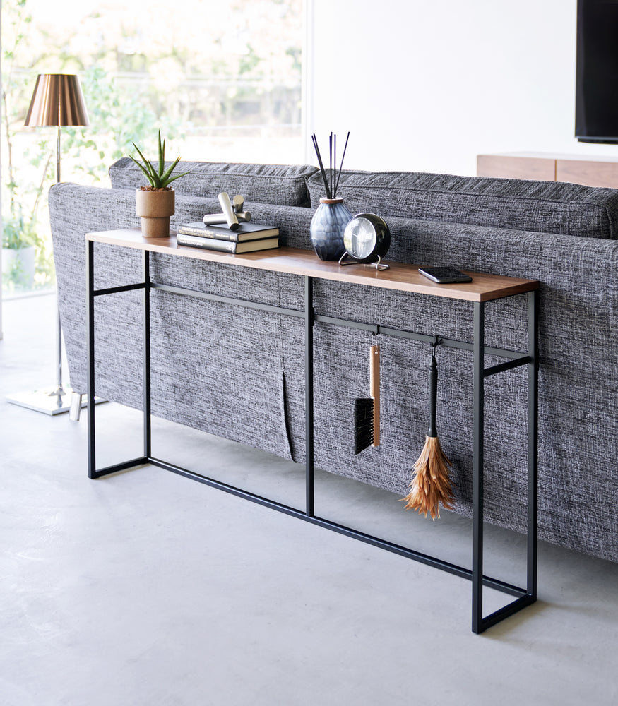 View 10 - Diagonal view of the Long Console Table by Yamazaki Home in black placed behind a gray couch in a living room.