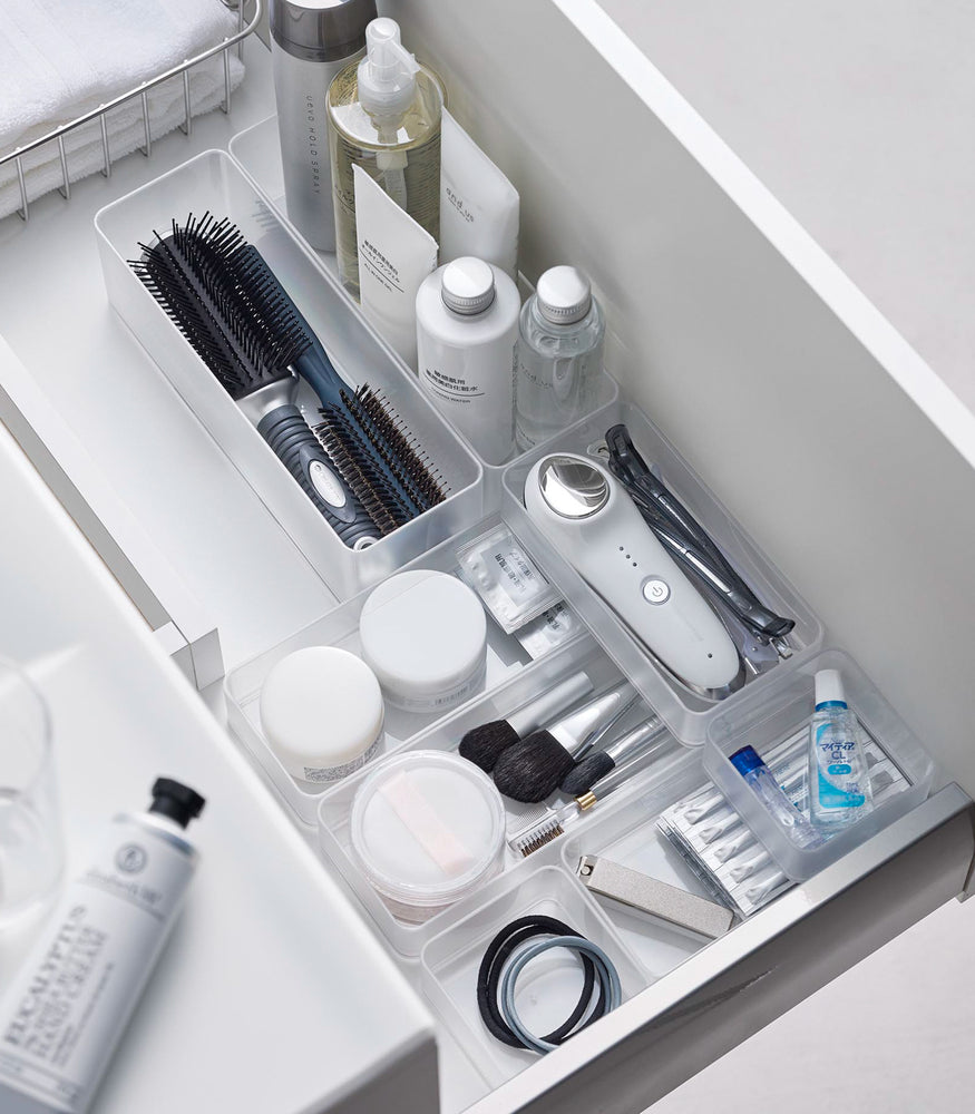 View 8 - Four different sizes of stackable clear organizers—small, medium, large, and deep—are neatly placed in a bathroom drawer. Made from transparent material, they accommodate items like brushes and sanitary products, showcasing their clarity and stackability.